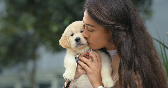 Woman kiss puppy with hug outdoor, animal and love, friends with pet care and affection with bonding. Female person with dog in city, mockup space with adoption and friendship, cuddling and loyalty