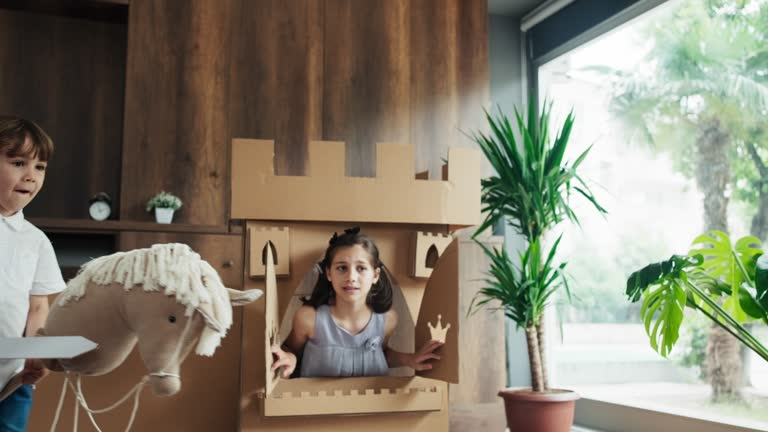 Princess, Prince And Witch Playing Role Play Game At Home With Castle Made Of Cardboard