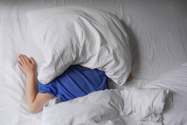istock woman sleeping in bed with pillow over her head 1497156866