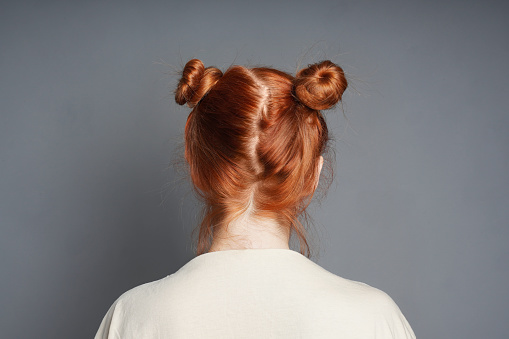 back view of red-haired woman with messy space buns hairstyle