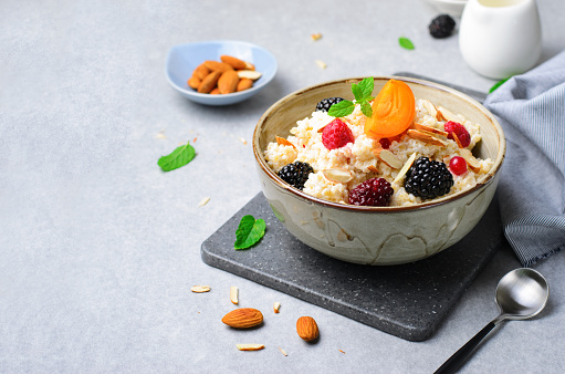 Spelt Porridge with Fruits, Berries, and Nut Topping, Healthy Breakfast or Snack on Bright Backround