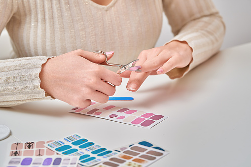Woman cutting and shaping her nails after applying nail decal.