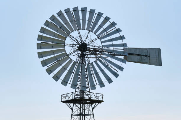The metal blades of an american wind engine under a blue sky.