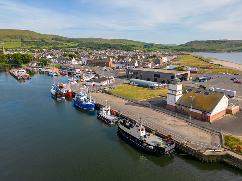 This aerial drone photo shows the small harbour town of Girvan in Ayshire, western Scotland. This town has a small port with several fishing boats.
