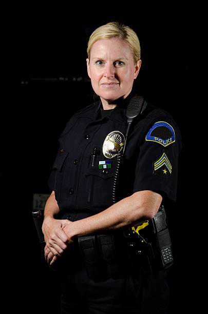 Police officer posing with a straight back & hands in front a female police officer standing in the night during her shift. female police officer stock pictures, royalty-free photos & images