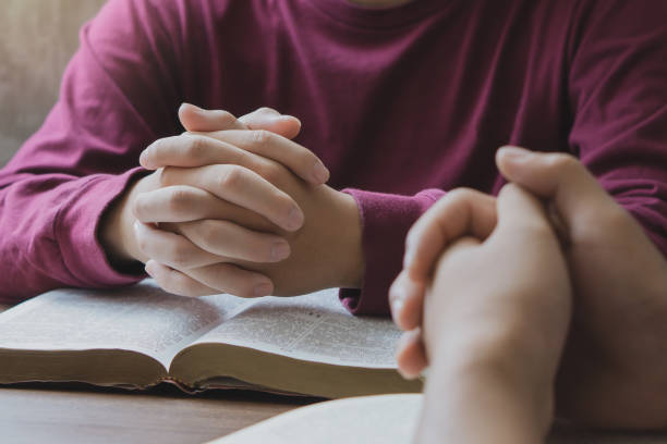 istock Prayer meeting concept.Colleagues shaking hands reading scriptures and praying to God at work place.Prayer, trust, hope, gratitude concept 1497168189