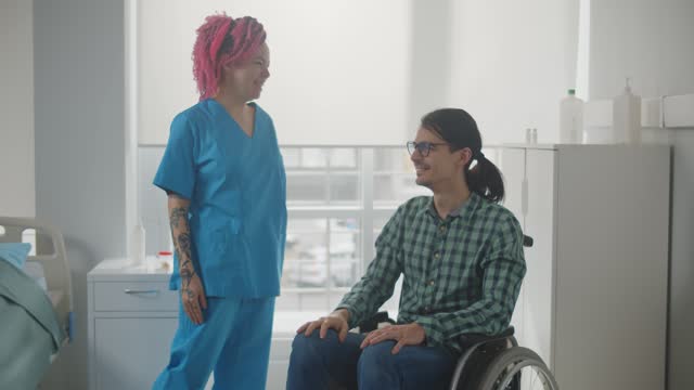 Smiling female nurse and male patient in wheelchair sharing secret hand gesture