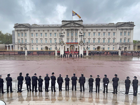 Police waiting outside Buckingham Palace in the rain on Coronation Day