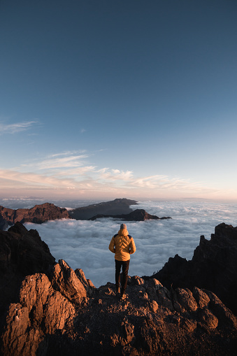 A sheltered mountaineer observing the landscape of the Caldera De Taburiente from the top of Roque De Los Muchachos at sunset on the Canary Island of La Palma.