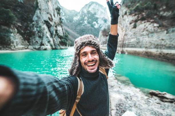 istock Handsome young man with backpack taking selfie outdoors - Happy hiker standing in front of mountains - Travel blogger enjoying nature view on summer trip 1497180745