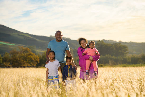 retrato de família africano ao ar livre iluminado de volta em um campo ao pôr do sol - life back lit people happiness - fotografias e filmes do acervo