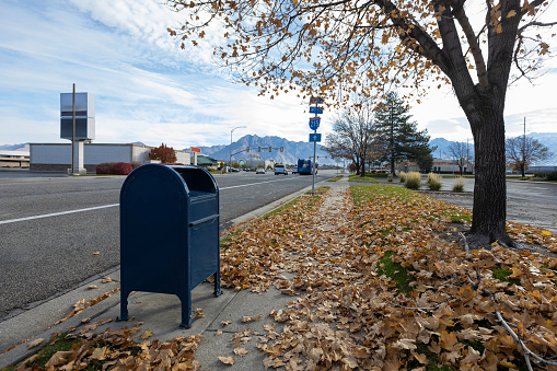 Sidewalk covered with a mailbox and some autumn leaves on the ground in Salt Lake City, Utah, United States