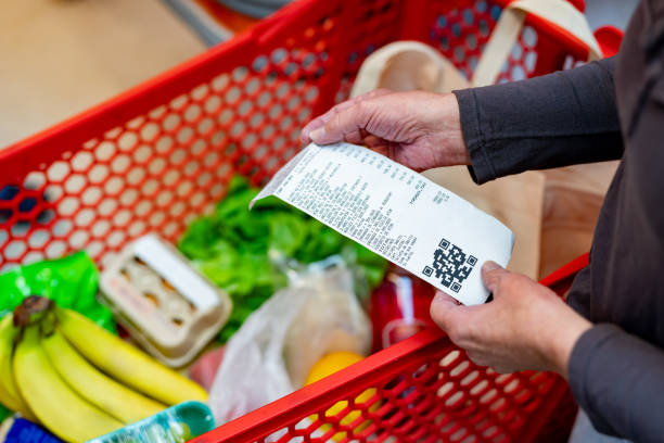 Close up of unrecognizable customer checking her receipt after purchasing groceries in the supermarket stock photo