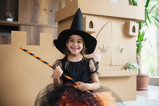 Little Witch Playing Role Play Game At Home With Castle Made Of Cardboard