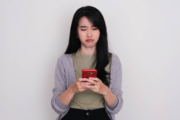 istock Young Asian woman texting on her phone with unhappy expression 1497197537