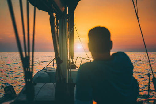 Man enjoying looking at sunset from sailboat. Model released.