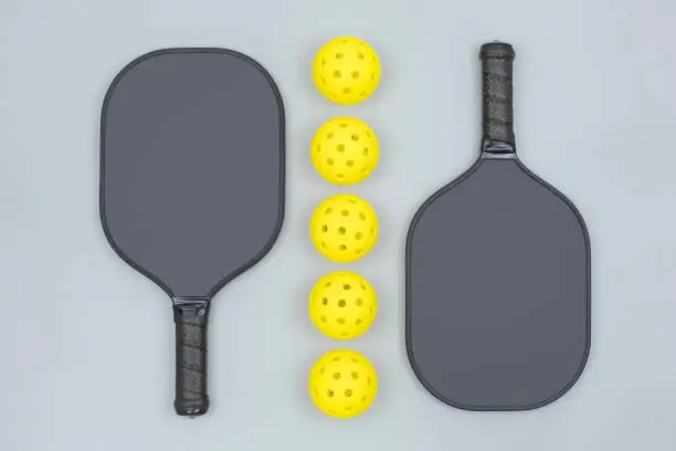 Photo of Pickleball paddles with five balls on gray