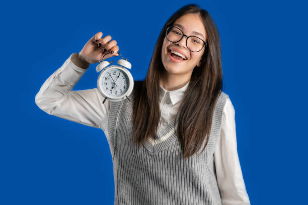 istock Happy student girl with alarm clock on blue background. Early morning, correct day routine, living in moment, appreciate every minute of life, youth 1497204766