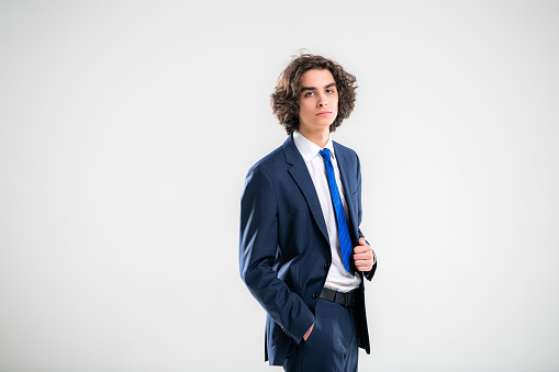 Portrait of a handsome young man in dark blue business suit on a white background.