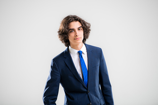 Portrait of a handsome young man in dark blue business suit on a white background.