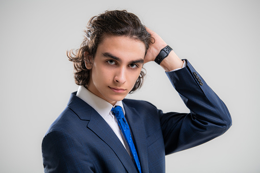 Portrait of a handsome young man in dark blue business suit on a white background.