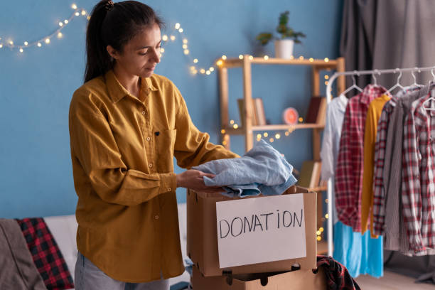 istock Donation concept. Woman preparing her used old clothes in a donate box 1497209236
