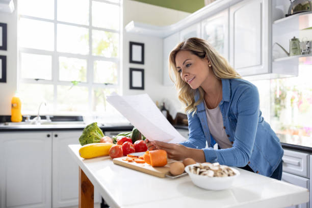 istock Woman reading a recipe while cooking dinner at home 1497209448