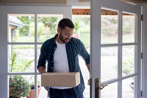 Happy Latin American man receiving a package at home - online shopping concepts