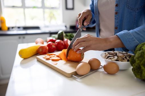 Close-up on a woman cooking at home and chopping vegetables in the kitchen