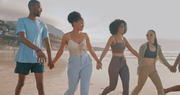 istock Holding hands, friends or walking at a beach for holiday vacation while bonding or laughing together. Happy people, smile or funny men and women group relaxing at seashore on an ocean trip in Miami 1497209711