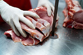 Close up shot of butcher cutting a block of por with an electric saw