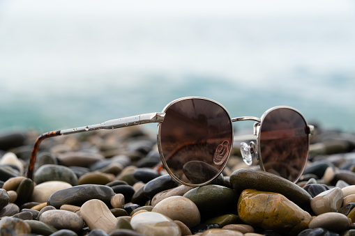 Sunglasses lying on a rocky shore against the backdrop of sea waves. High quality photo