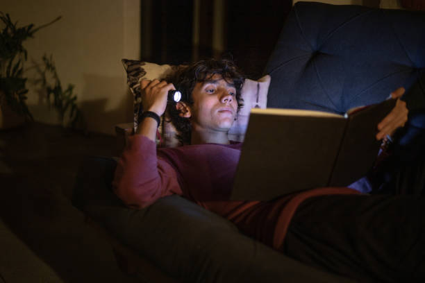 istock Teenager reading a book with a flashlight 1497212394
