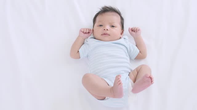 Cute little baby girl lying on the bed moving his arms and legs,slow motion shot.