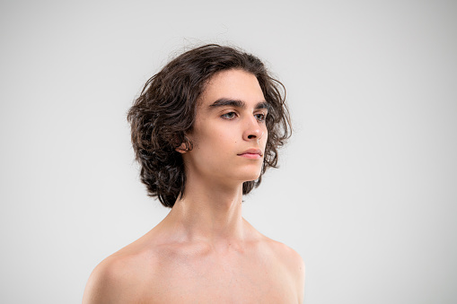 Portrait of a handsome young man with lush curly hair on white background