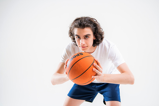 Portrait of a boy playing with basketball on white background