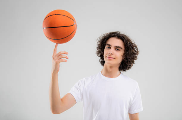 Player spinning basketball on finger against white background