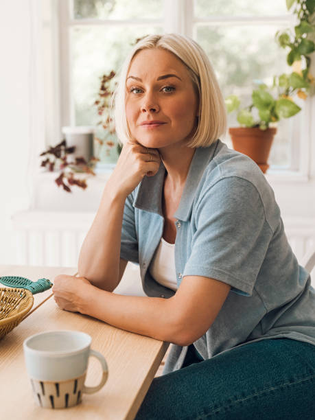 istock Woman at home indoors by her kitchen table drinking coffee 1497218727