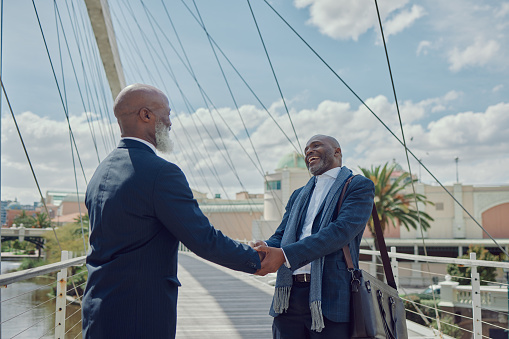 Corporate hand shake, happy and black people greeting, welcome and hello on urban city commute. B2B conversation bridge and African team, professional men or business partner with thank you handshake