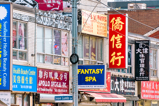 Toronto, Canada - June 4, 2023: Chinatown. A commercial building with multiple signs.  Some of the signs are in Chinese.