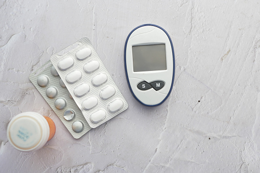 diabetic measurement tools and medical pills on table .