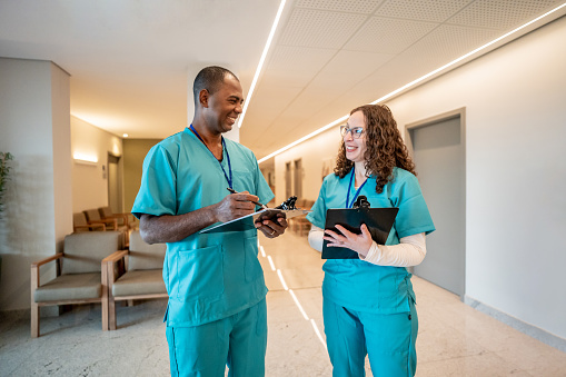 Nurse and male nurse talking in hospital corridor