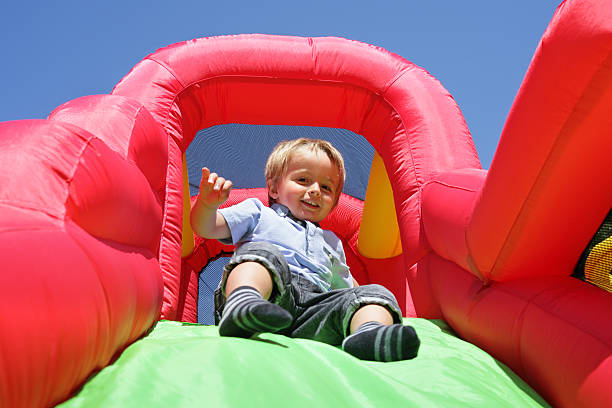 niño en tobogán inflable castillo inflable para saltar - inflatable child playground leisure games fotografías e imágenes de stock