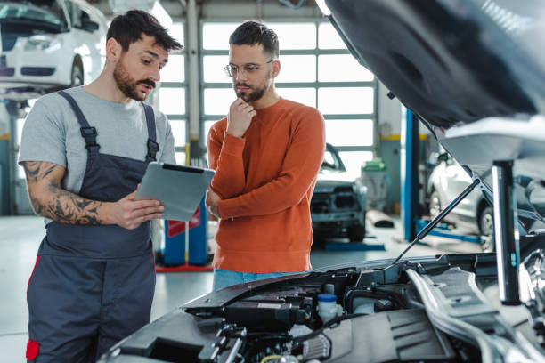 istock Customer and automotive technician talking  about the car problem in a workshop 1497239478