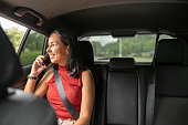 Happy young woman traveling by a taxi talking on her cell phone