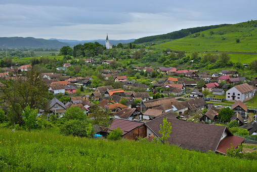Old transylvanian village during summer on a cloudy day with medieval christian church residing on the hill