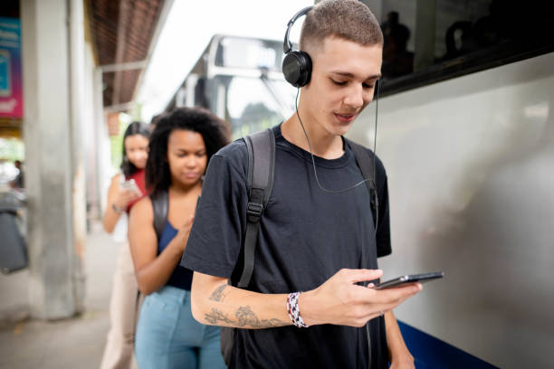 Young man watching a video on his phone while waiting for a bus