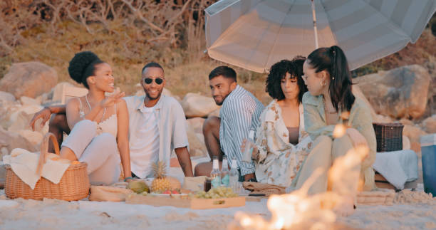 istock Campfire, picnic or people at beach for holiday vacation while bonding, laughing or drinking beer together. Happy smile, diversity or funny friends relaxing on seashore on ocean trip in Miami, USA 1497243608