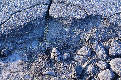 A Close Up Of Large Road Pot Hole With Cement And Rocks Inside