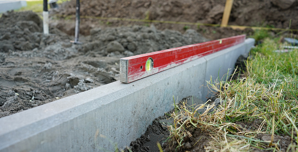 Level on the concrete kerb. Leveling on the construction site. Work zone. Measurement. Red level.